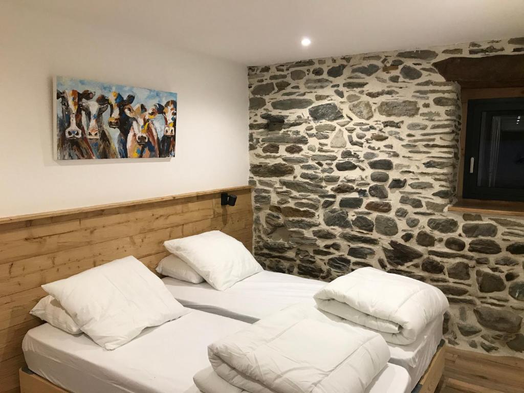 - 2 lits dans une chambre avec un mur en pierre dans l'établissement Les Granges de Clarabide, à Loudenvielle