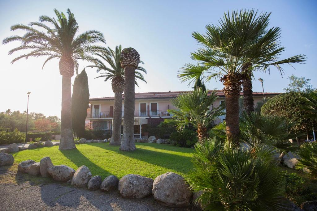 un jardin avec des palmiers et des rochers devant un bâtiment dans l'établissement Hotel Fabricia, à Portoferraio
