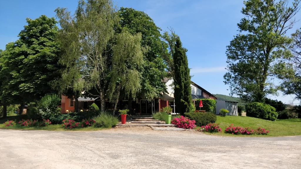une maison avec des arbres et des fleurs dans l'allée. dans l'établissement Camping Au Tour de l'Aveyron, à LʼHospitalet-du-Larzac