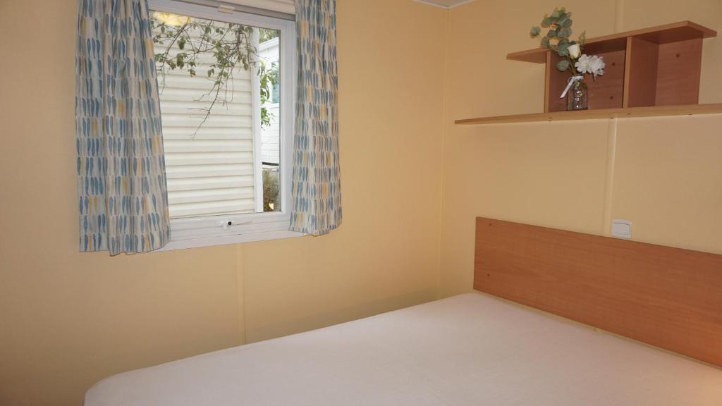 - une chambre avec une fenêtre, un lit et une étagère dans l'établissement Chalets met buitenkeuken op Camping Leï Suves - JoyCasa, à Roquebrune-sur Argens