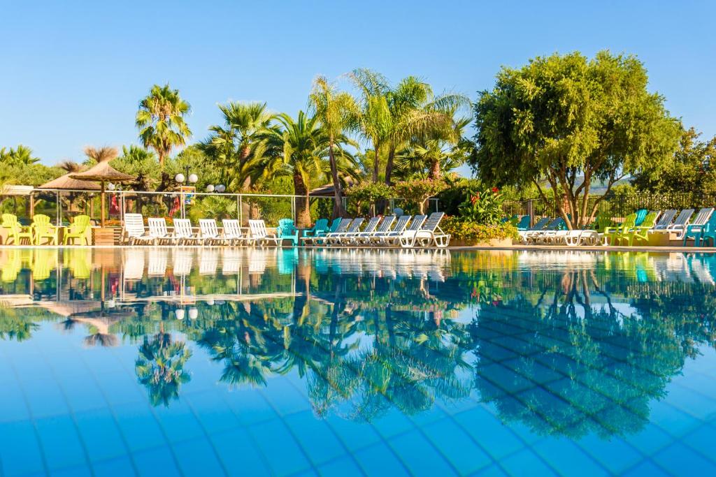 - une piscine dans un complexe avec des chaises et des palmiers dans l'établissement Chalets met buitenkeuken op Camping Leï Suves - JoyCasa, à Roquebrune-sur Argens 28 autres photos
