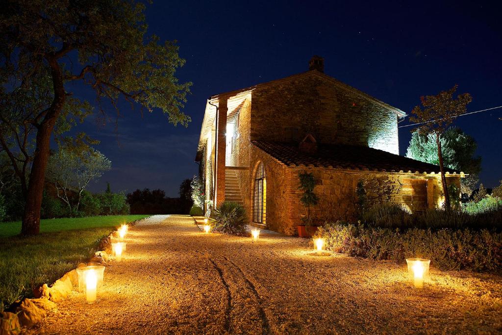 un ancien bâtiment en pierre avec des lumières sur une route dans l'établissement Villa in Agello, à Agello