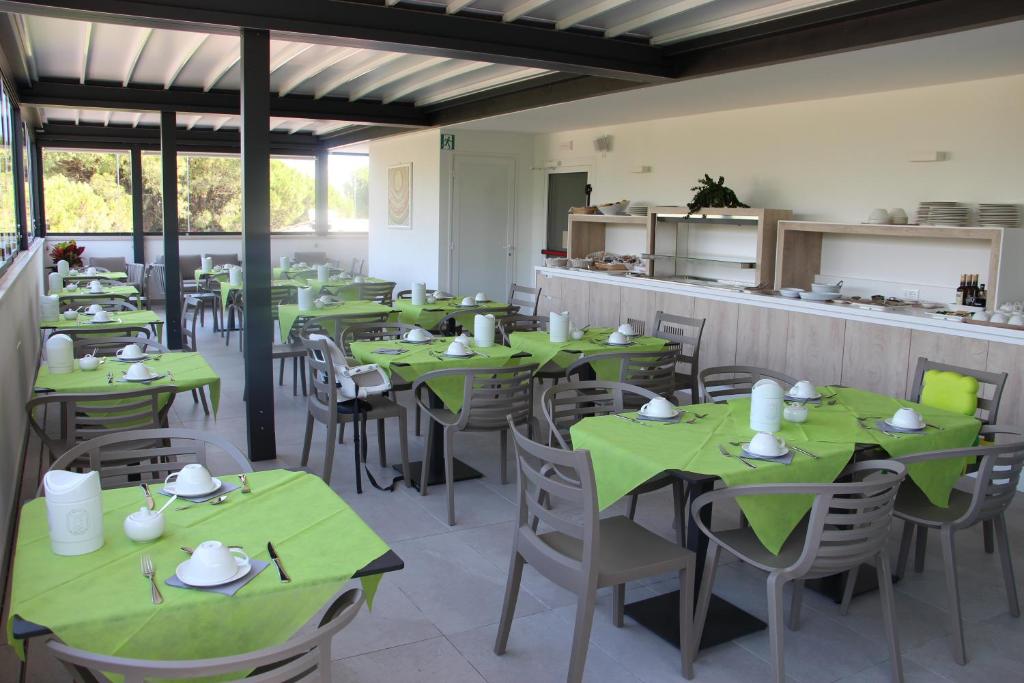 une salle à manger avec des tables et des chaises vertes dans l'établissement Hotel La Pigna, à Lignano Sabbiadoro