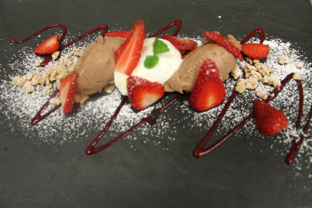 un dessert avec des fraises sur une assiette noire dans l'établissement Hotel La Pigna, à Lignano Sabbiadoro