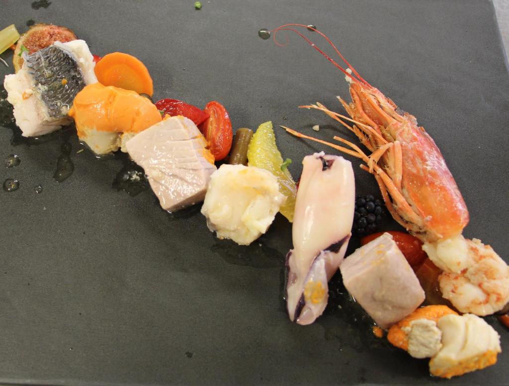 un tas de nourriture sur une assiette noire dans l'établissement Hotel La Pigna, à Lignano Sabbiadoro 11 autres photos