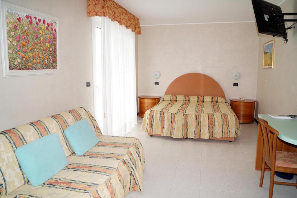 un salon avec un canapé et un lit dans l'établissement Hotel La Pigna, à Lignano Sabbiadoro