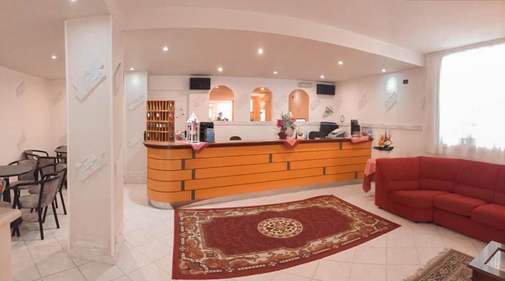 un salon avec un canapé rouge et un comptoir dans l'établissement Hotel Admiral, à Pinarella