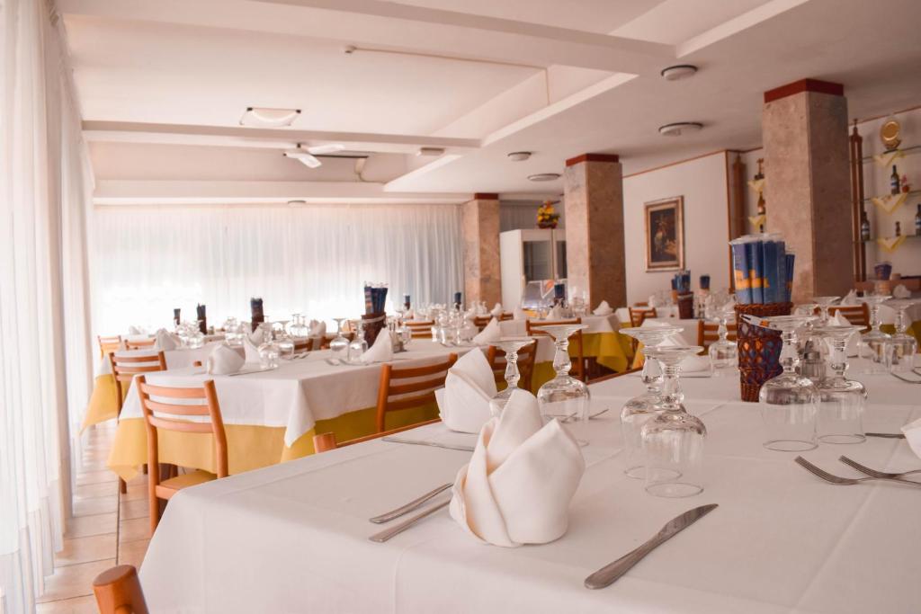 une salle à manger avec des tables et des chaises blanches dans l'établissement Hotel Admiral, à Pinarella