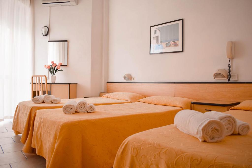 une chambre avec trois lits avec des serviettes dessus dans l'établissement Hotel Admiral, à Pinarella 80 autres photos