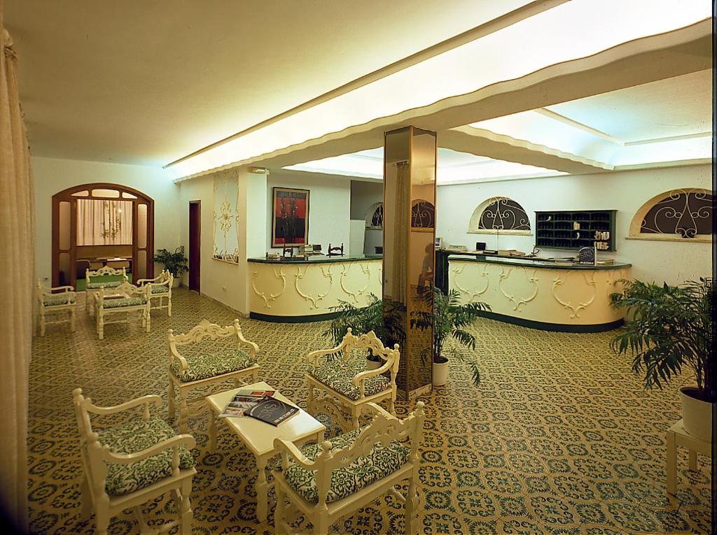 un hall d'entrée avec des chaises, une table et un comptoir dans l'établissement Hotel Lido Mediterranee, à Taormine