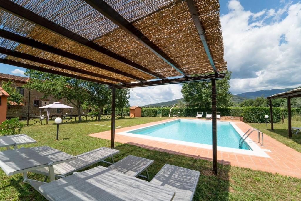 une pergola au-dessus d'une piscine avec des chaises longues et une piscine dans l'établissement La Gropina Di Loro Ciuffenna, à Loro Ciuffenna