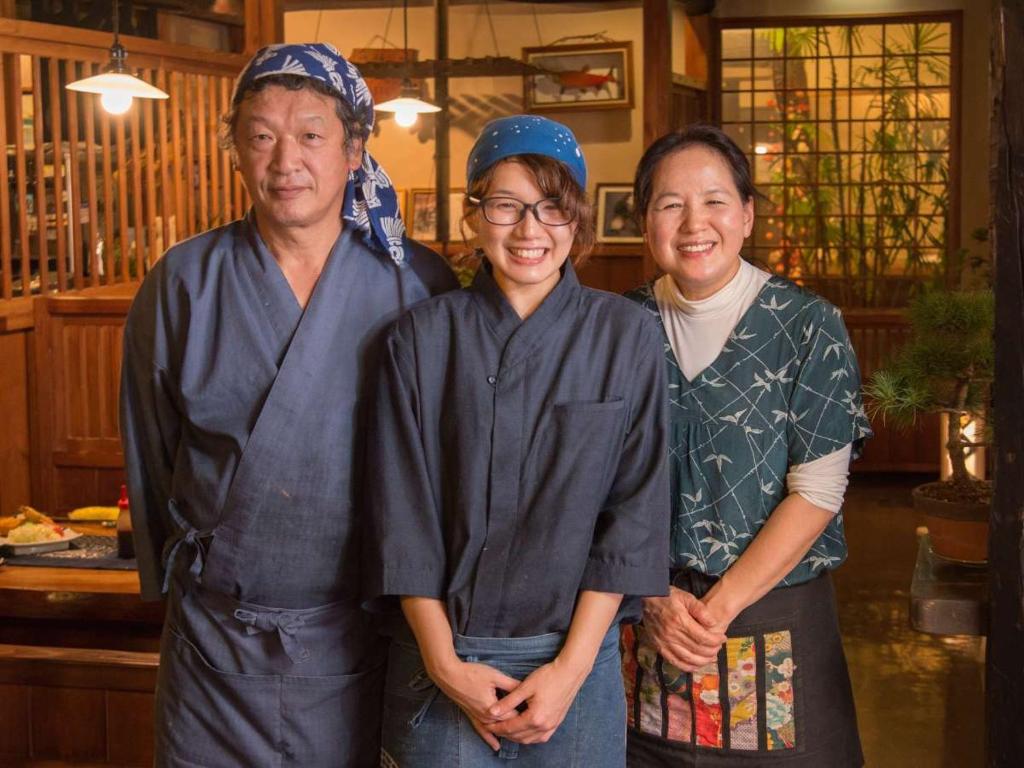 un groupe de trois personnes posant pour une photo dans l'établissement Oyado Ichifuji, à Nikkō