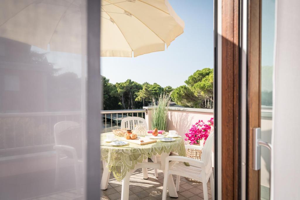 une table et des chaises sur un balcon avec un parasol dans l'établissement Bosco Canoro Bibione Resort, à Bibione