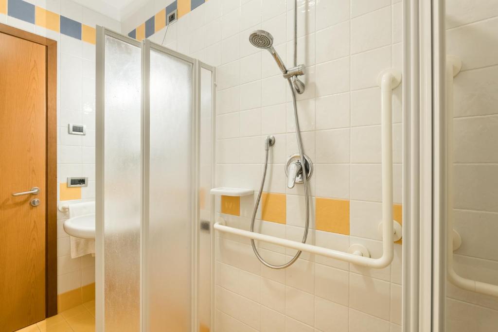 une douche dans une salle de bain avec une porte vitrée dans l'établissement Bosco Canoro Bibione Resort, à Bibione