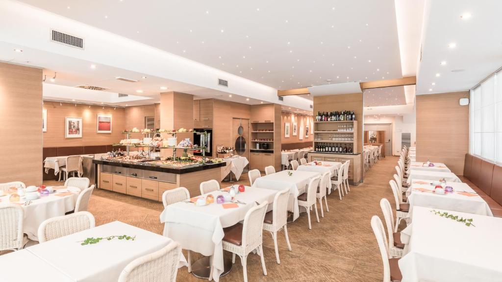 une salle à manger avec des tables blanches et des chaises blanches dans l'établissement Hotel Katja, à Bibione