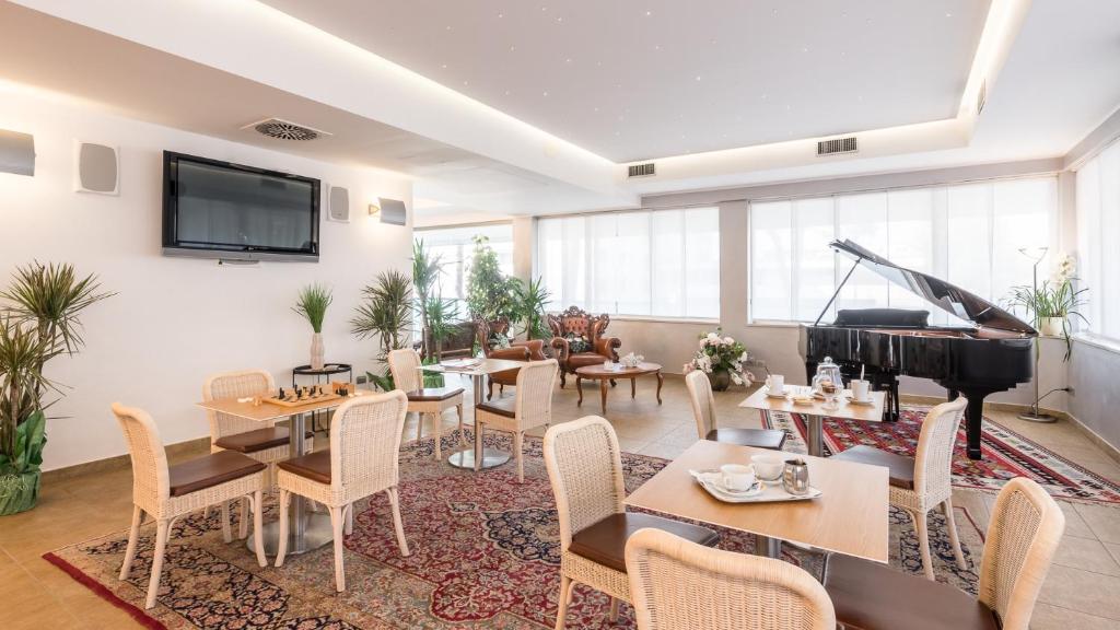 - un salon avec un piano, des tables et des chaises dans l'établissement Hotel Katja, à Bibione