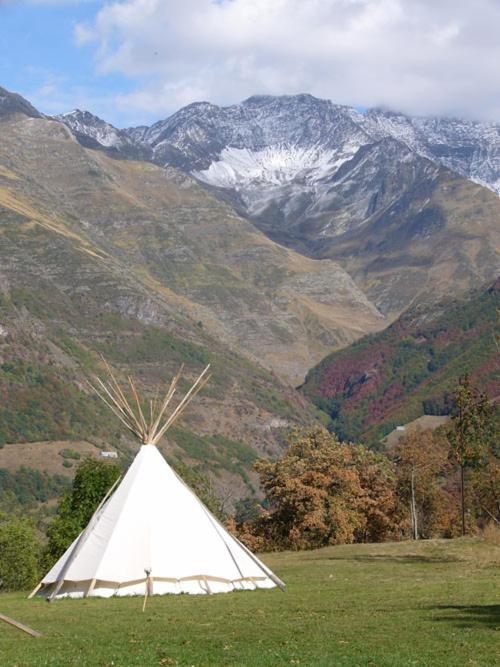 un tipi blanc dans un champ avec des montagnes en arrière-plan dans l'établissement Tipi nature double, à Gavarnie