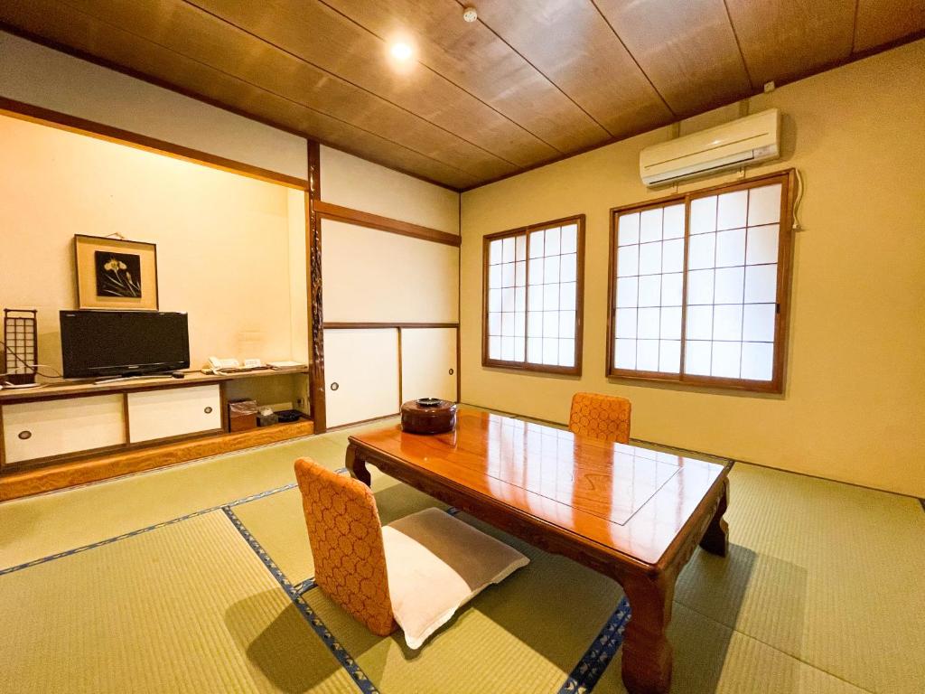 une salle à manger avec une table et des chaises en bois dans l'établissement Hotel Sumire ふぐ料理を愉しむ料理宿, à Shimonoseki