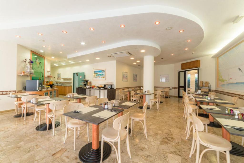 un restaurant avec des tables et des chaises dans une salle dans l'établissement Hotel Airone, à Bibione