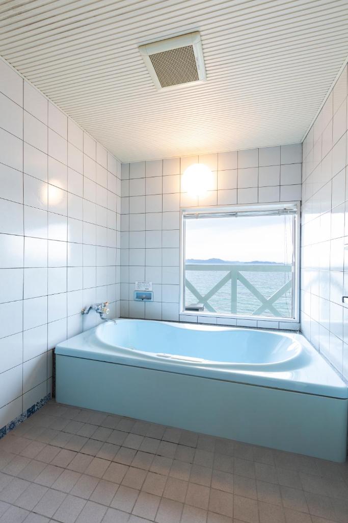 une baignoire dans une salle de bain avec une fenêtre dans l'établissement Hotel Liberty Matsuyama (Adult Only), à Matsuyama