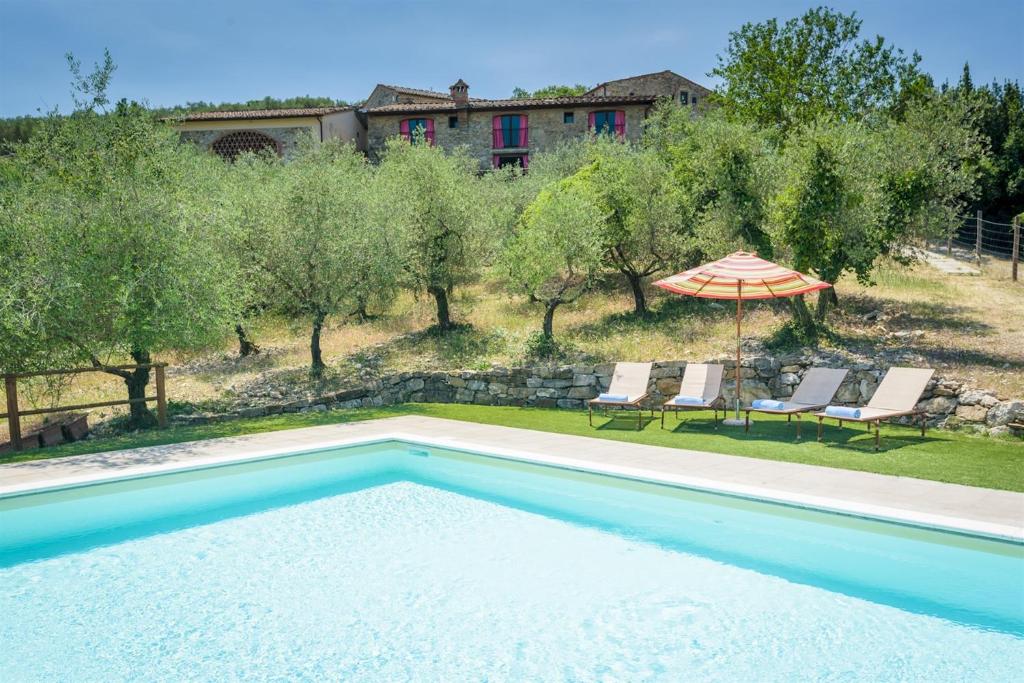 une piscine avec deux chaises et un parasol dans l'établissement Villa La Poiana 10 Emma Villas, à Radda in Chianti