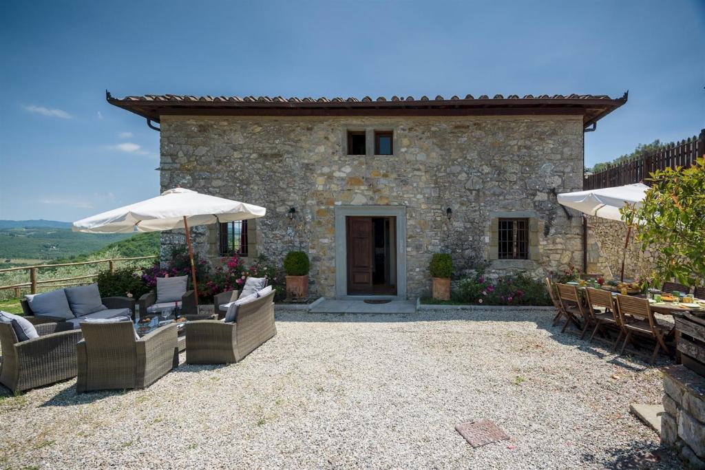 un patio extérieur avec des chaises et des parasols en face d'un bâtiment dans l'établissement Villa La Poiana 10 Emma Villas, à Radda in Chianti