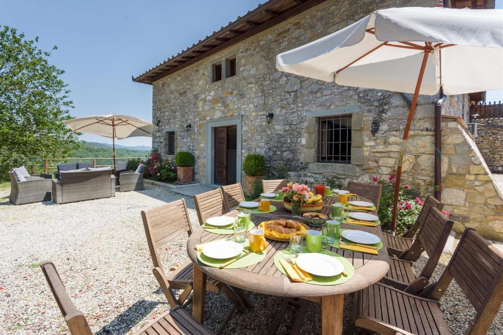 - une table avec de la nourriture et un parasol sur la terrasse dans l'établissement Villa La Poiana 10 Emma Villas, à Radda in Chianti