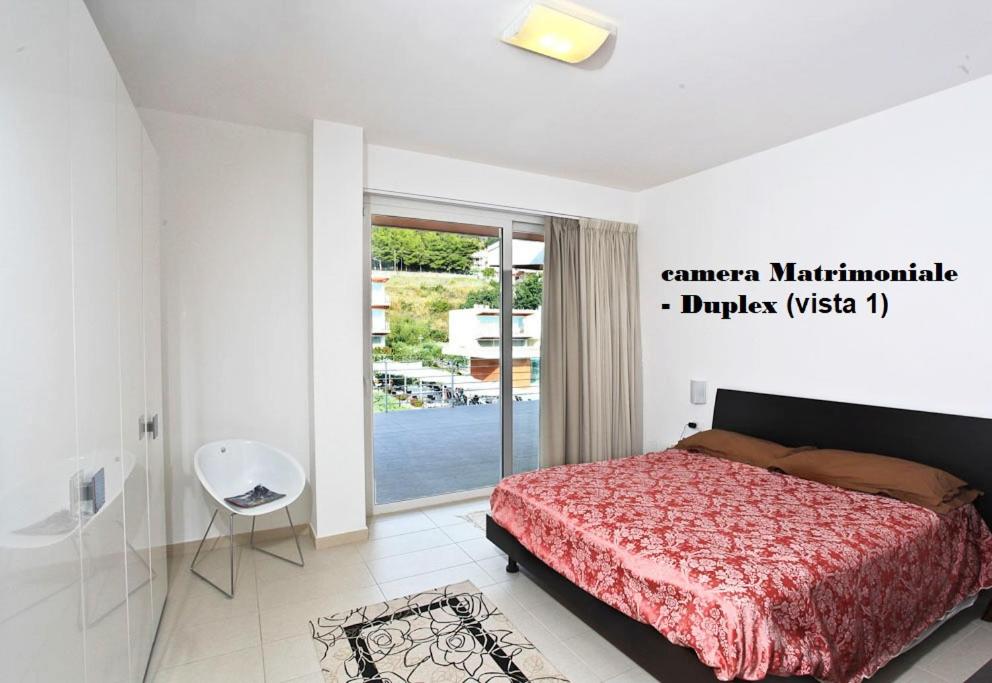 une chambre avec un lit et une porte coulissante en verre dans l'établissement Sporting Club Resort, à Praia a Mare