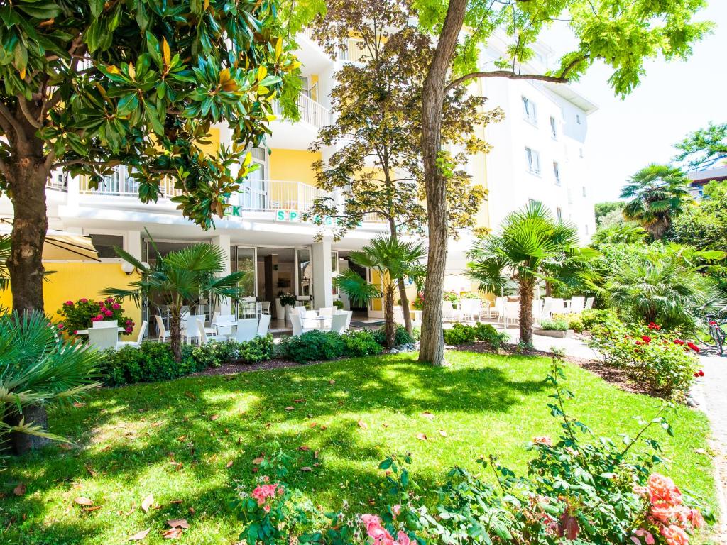 un jardin en face d'un bâtiment planté d'arbres et de fleurs dans l'établissement Hotel Park Spiaggia, à Grado 21 autres photos