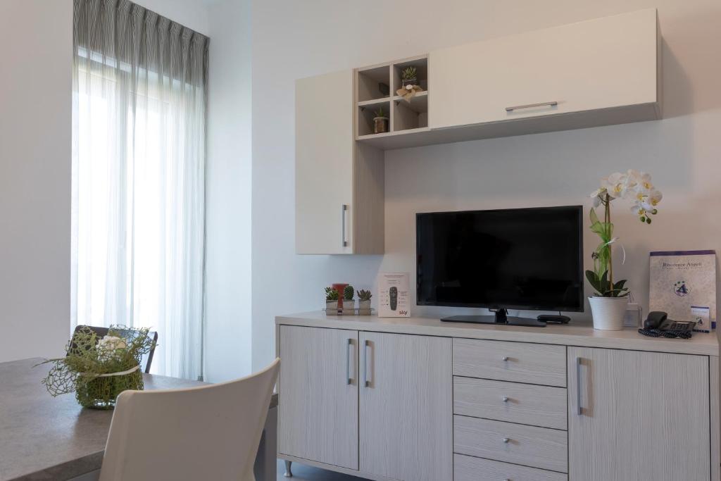 - un salon avec une télévision sur une commode blanche dans l'établissement Residence Hotel Angeli, à Rimini