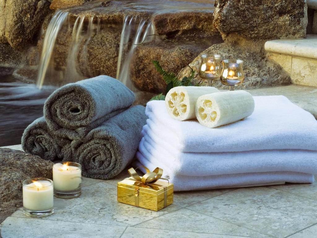 - une pile de serviettes et de bougies à côté d'une cascade dans l'établissement COLONNA RESORT, a Colonna Luxury Beach Hotel, Porto Cervo, à Porto Cervo