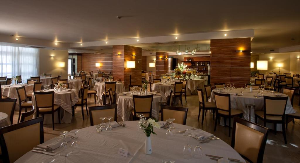 une salle à manger avec tables et chaises avec du linge de table blanc dans l'établissement Virgilio Grand Hotel, à Sperlonga