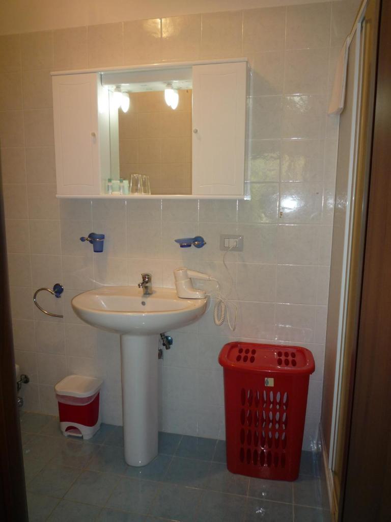 une salle de bain avec un lavabo et une poubelle rouge dans l'établissement La Valle Verde hotel ristorante pizzeria, à Zambrone