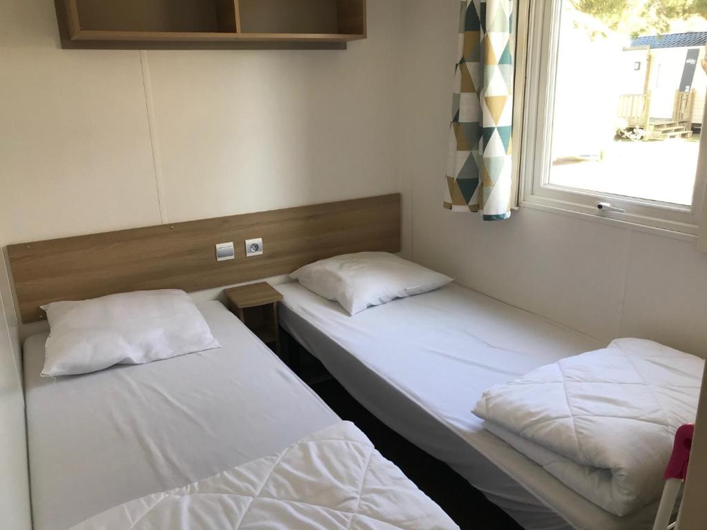 deux lits assis dans une pièce avec une fenêtre dans l'établissement Mobil Home camping Mar Estang bord de plage, à Canet