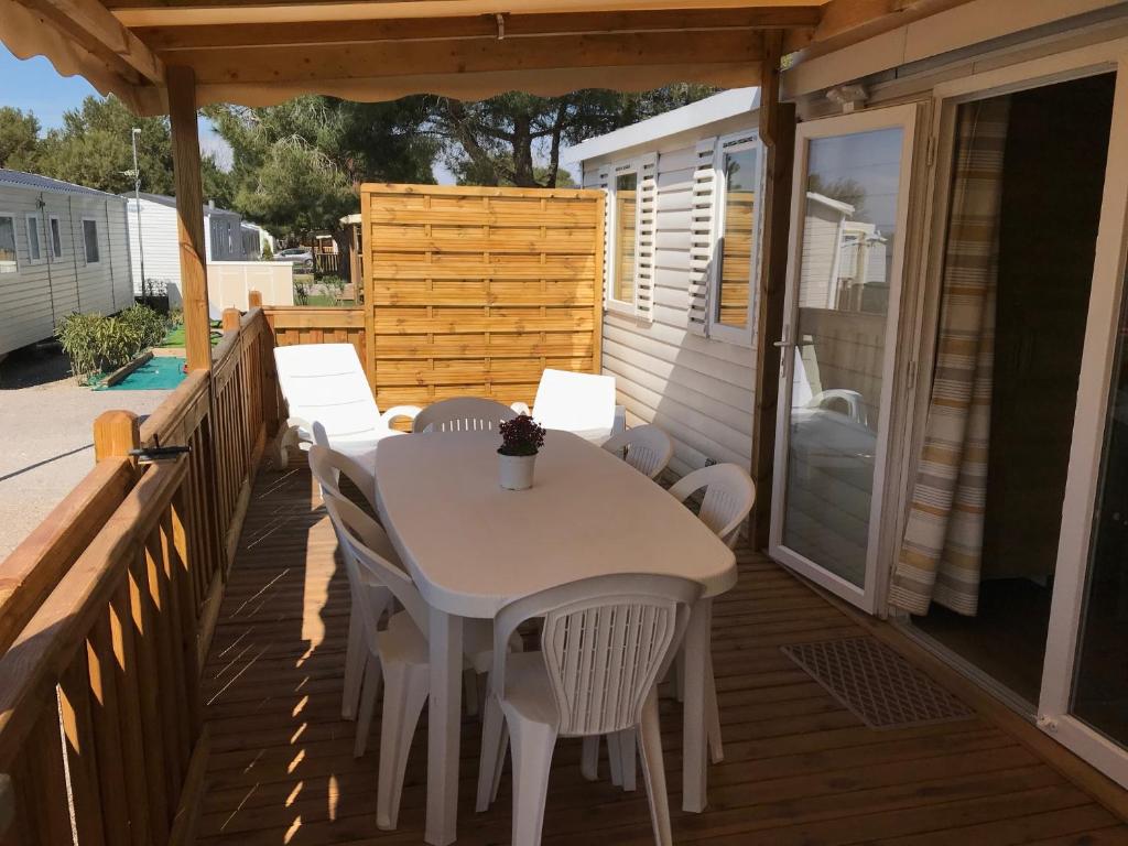 une table et des chaises blanches sur une terrasse dans l'établissement Mobil Home camping Mar Estang bord de plage, à Canet