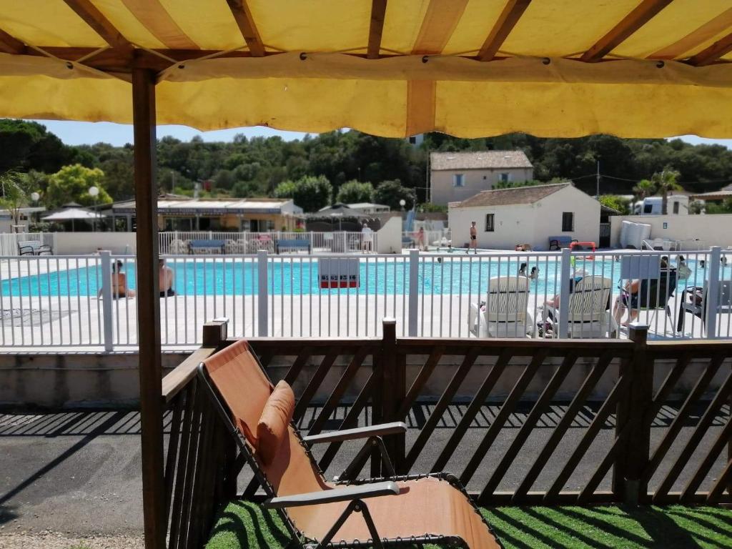 - une terrasse avec une chaise et un parasol à côté de la piscine dans l'établissement vacances familiales dans camping avec piscine, à Fréjus