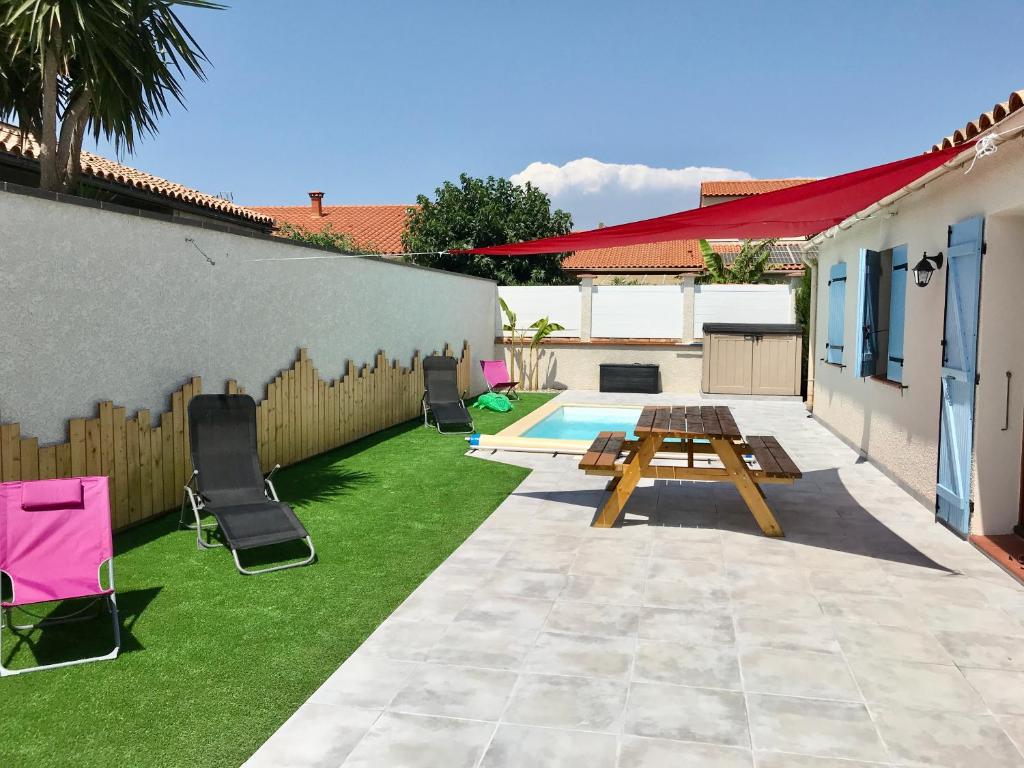 une cour arrière avec une table, des chaises et une piscine dans l'établissement Gîte de Leni - Maison avec piscine, à Torreilles