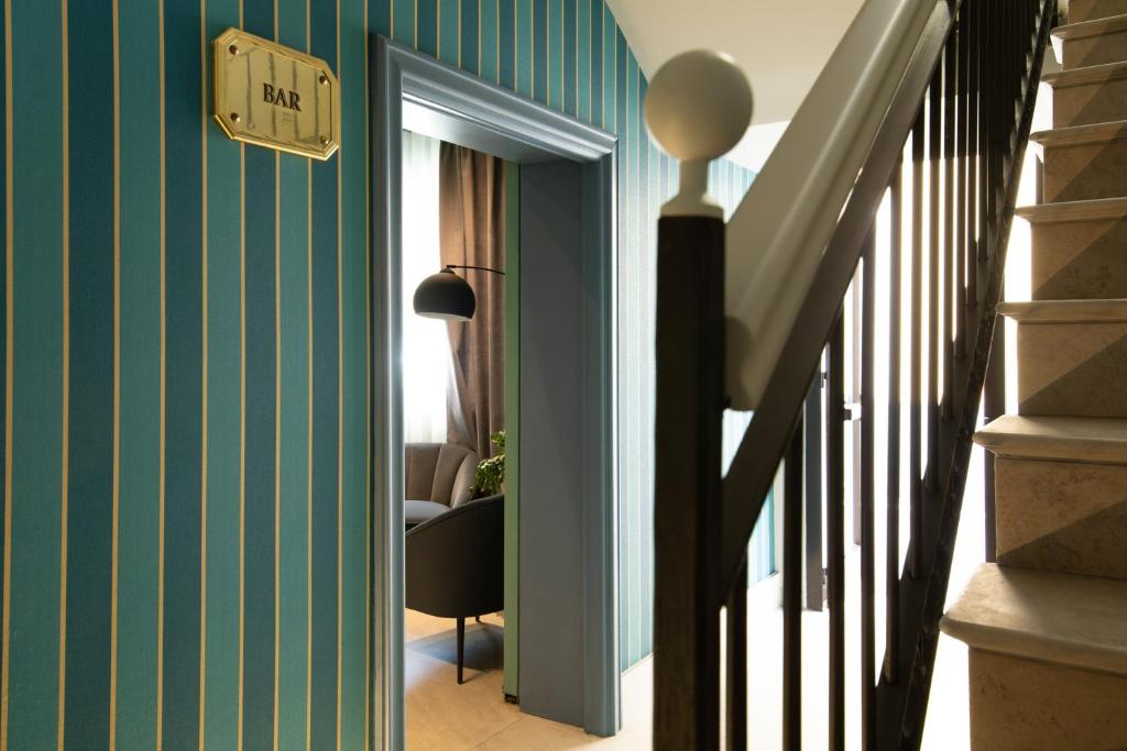 un couloir aux murs à rayures vertes et un escalier dans l'établissement Hotel Enzo, à Porto Recanati