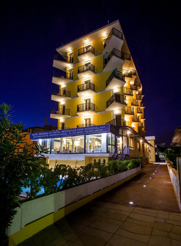 un grand immeuble d'appartements avec éclairage la nuit dans l'établissement Hotel Mondial, à Lido di Jesolo
