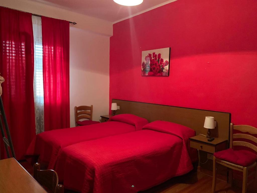 une chambre rouge avec deux lits avec des draps rouges dans l'établissement Hotel Turano, à Castel di Tora
