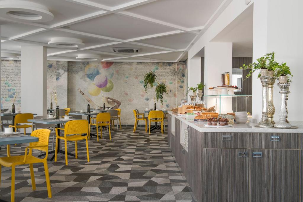 un restaurant avec des chaises jaunes, un comptoir et des tables dans l'établissement Hotel Rainbow ***S, à Rimini