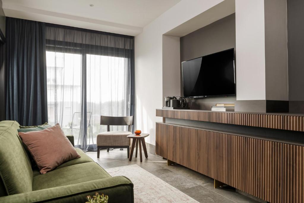 un salon avec un canapé vert et une télévision à écran plat dans l'établissement Coast Hotel & Spa - Adults Only Aperto tutto l'anno, à Milano Marittima