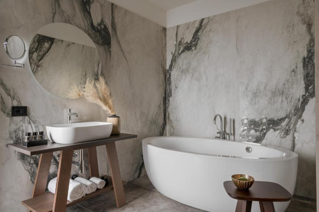 La salle de bains est pourvue d'une grande baignoire blanche et d'un lavabo. dans l'établissement Coast Hotel & Spa - Adults Only Aperto tutto l'anno, à Milano Marittima