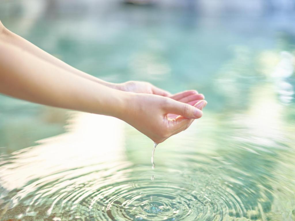 une main tient l'eau d'un bassin d'eau dans l'établissement Ooedo Onsen Monogatari Gero Bekkan, à Gero