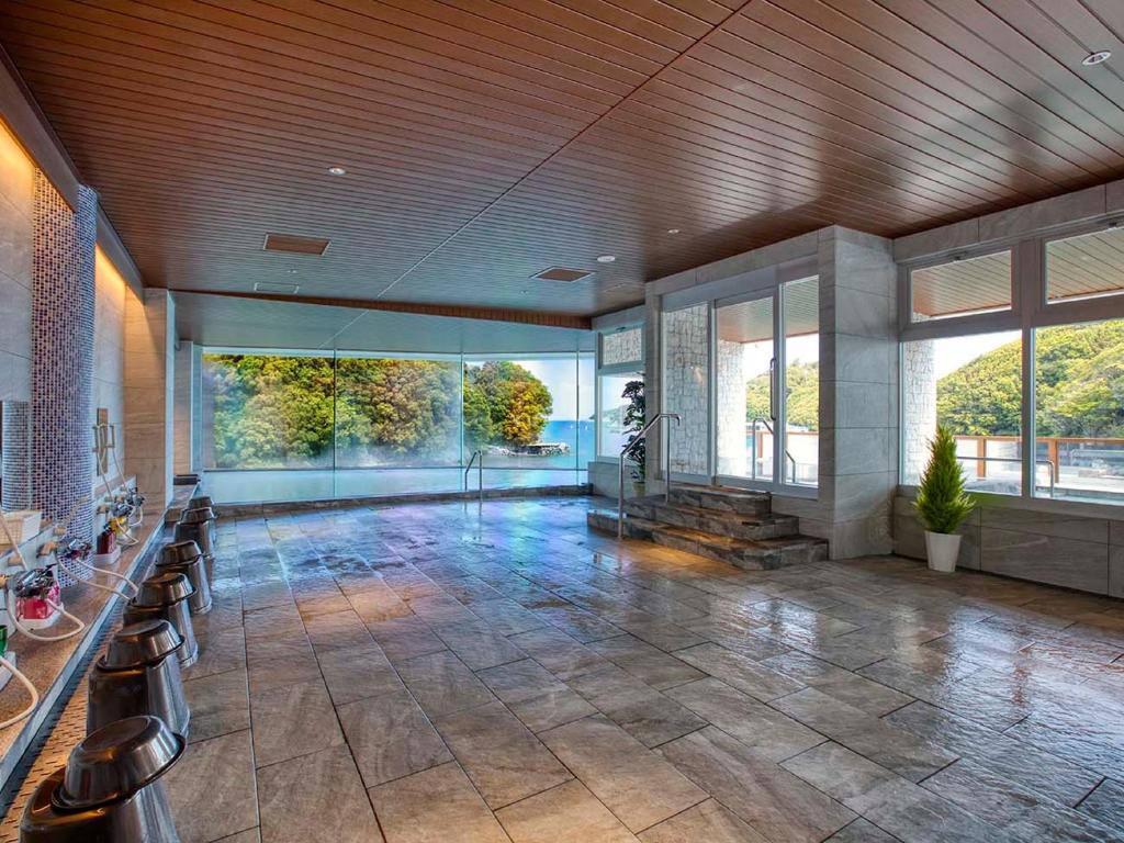 une grande pièce avec un hall avec des chaises et des fenêtres dans l'établissement Ooedo Onsen Monogatari Premium Toba Saichoraku, à Toba