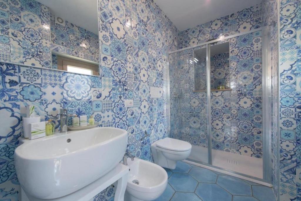 La salle de bains bleue et blanche est pourvue d'un lavabo et de toilettes. dans l'établissement VIlla del Presidente, à Praiano