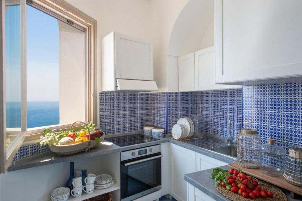 - une cuisine avec des placards blancs et un bol de fruits sur le comptoir dans l'établissement VIlla del Presidente, à Praiano 10 autres photos