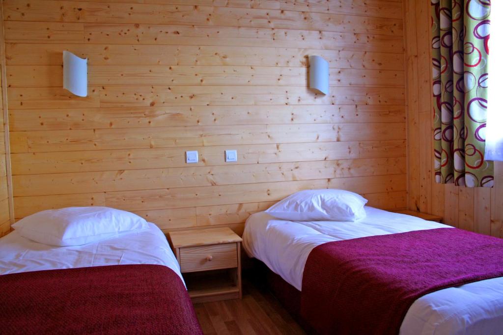 deux lits dans une chambre aux murs en bois dans l'établissement Chalets de Trémontagne 3 étoiles, à Prénovel