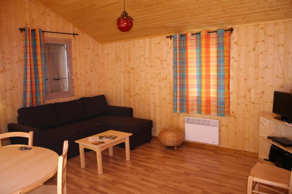 un salon avec un canapé noir et une table dans l'établissement Chalets de Trémontagne 3 étoiles, à Prénovel