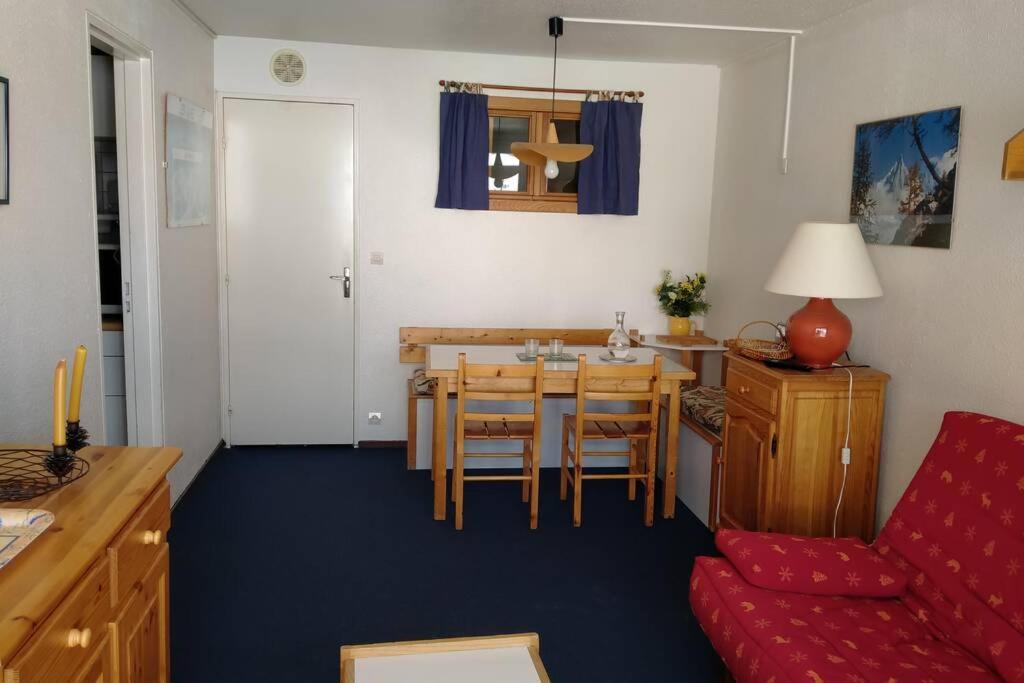 un salon avec une table et un canapé rouge dans l'établissement Studio 4pers vue piste, au Corbier
